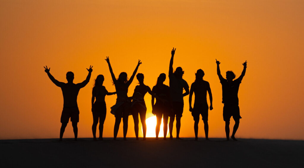 Grupo de pessoas no trekking nos Lençóis Maranhenses ao por do sol