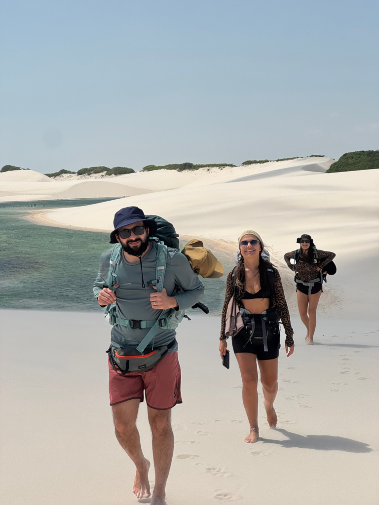Grupo de caminhantes nas dunas junto a uma lagoa dos Lençóis Maranhenses