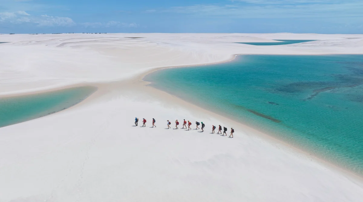Grupo caminhando entre dunas e lagoas dos Lençóis Maranhenses